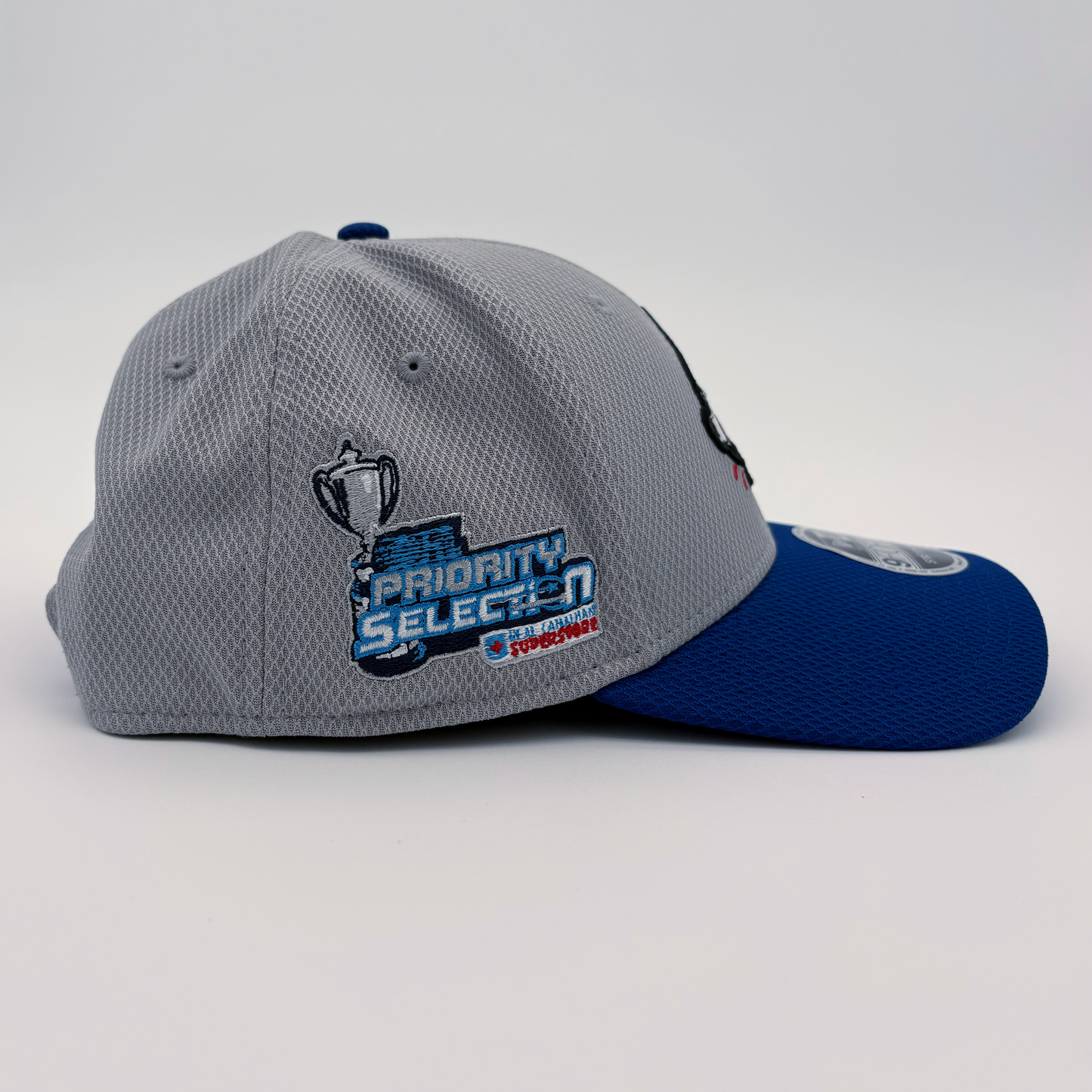A side view of the grey and blue Sudbury Wolves' OHL Priority Selection hat, with the OHL Priority Selection logo embroidered on the side.